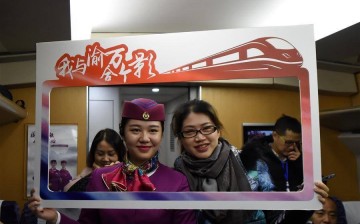 A passenger poses for a group photo with a train attendant on a train running on Chongqing-Wanzhou high-speed railway, southwest China, Nov. 28, 2016.