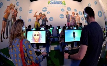 Visitors try out the game 'SIMS 4' at the Electronic Arts stand at the 2014 Gamescom gaming trade fair on August 14, 2014 in Cologne, Germany.