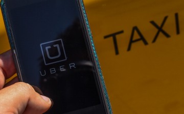 The smart phone app Uber logo is displayed on a mobile phone next to a taxi on July 1, 2014 in Barcelona, Spain. 