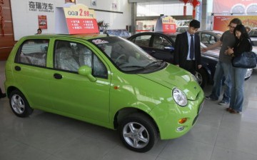 Customers view a small QQ model car at a showroom from a Chinese auto manufacturer.