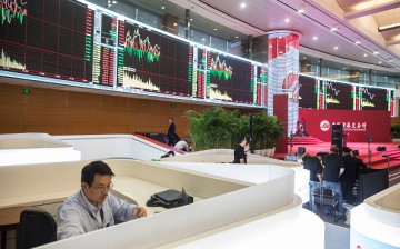 A man monitors stock changes on the electronic boards at the Shanghai Stock Exchange.