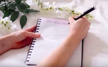 An individual is starting to write her New Year's resolution for 2017 on her notebook. 
