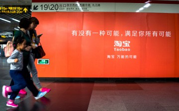 Commuters walk past a poster advertising Taobao services in a subway in Shanghai.