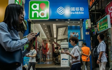 Pedestrians use their smartphones while walking past a China Mobile Ltd. store in Hong Kong, China.