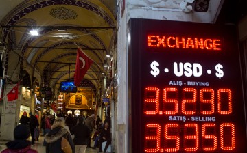 People walk past a sign showing the exchange rate for the U.S. dollar.