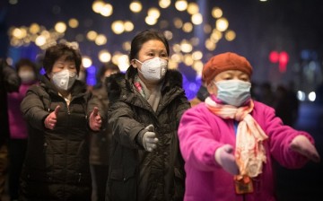 People wearing masks dance on a street, as red alert was released on December 16, warning that heavy smog would shroud the country's northern regions over the following two days.