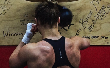 Ronda Rousey shows off her physique by posing in front of a speed bag at the gym she trains in. 