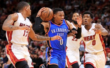 Russell Westbrook of the Oklahoma City Thunder drives on Josh Richardson and Rodney McGruder of the Miami Heat during a game at American Airlines Arena on December 27, 2016 in Miami, Florida. 