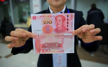 A bank staff shows the 100 yuan bill with new counterfeit features.