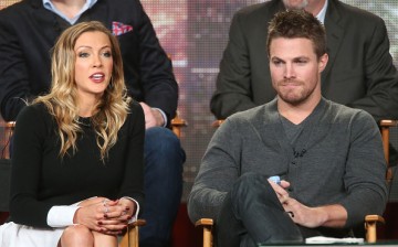 Katie Cassidy speaks as Stephen Amell listens onstage during the 'Arrow' and 'The Flash' panel as part of The CW 2015 Winter Television Critics Association press tour.