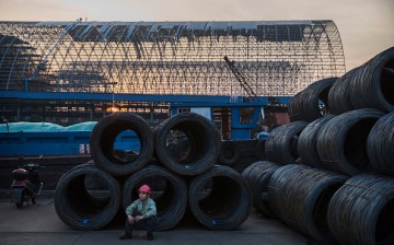 A worker takes a break as steel wire waits to be loaded onto barges in Changzhou, Jiangsu Province, on May 12, 2016.