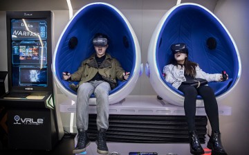 A Chinese couple wear virtual reality (VR) glasses in a VR arcade.