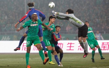 Shanghai Shenhua goalkeeper Wang Dalei punches away a shot from Da Costa Reinaldo Elias of Beijing Guoan in their matchup last Mar. 16, 2012.