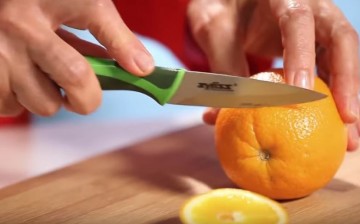 An orange, which is a good source of vitamin C, is being sliced and prepared for eating.