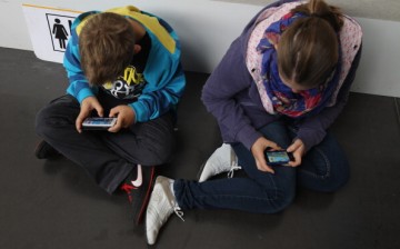  Children play video games on smartphones while attending a public event 