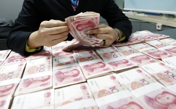 A Chinese clerk counts renminbi yuan banknotes at a bank in Huaibei, Anhui Province.