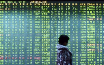 An investor walks past a screen showing stock market movements at a securities firm in Hangzhou.
