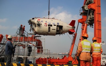 Workers install Jiaolong, China's manned deep-sea research submersible, onto its carrier.
