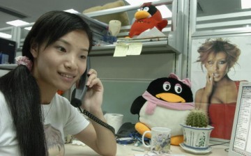 A worker makes a phone call beside an emblem of Tencent QQ instant messaging service, in the headquarters office of the Tencent Holdings Limited in Shenzhen.