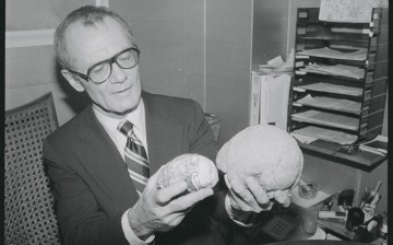 Dr. Robert Jastrow holds models of man's brain, showing its smaller size of 2 million years ago and the modern brain.