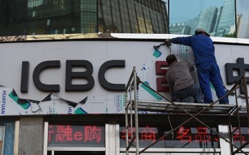Workers install a sign above the entrance to a branch of the Industrial and Commercial Bank of China.