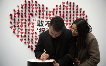 A couple write on a heart-shaped sticker at a shopping mall on Valentine's Day in Beijing.