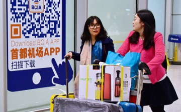 Two Chinese women arrive at Beijing Capital International Airport as they cart purchased goods from abroad.