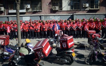 A group of food delivery drivers line up as they prepare for work along a street in Beijing.