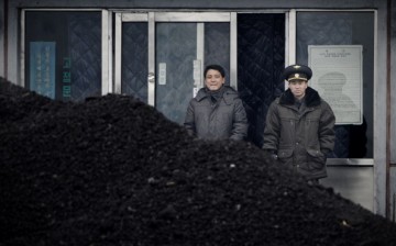 North Korean military officer (R) and a North Korean man (L) standing behind a pile of coal along the banks of the Yalu River northeast of the North Korean border town of Siniuju.