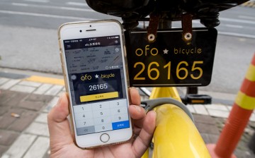 A passenger uses app on the phone to check mileage of a yellow rental bike at the service points of Zhoujiazui Road.