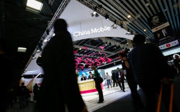 An attendee uses a mobile device as she passes the China Mobile stand on the second day of the 2017 Mobile World Congress (MWC) in Barcelona, Spain.