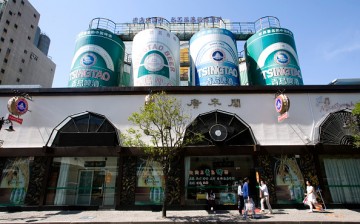 Pedestrians walk outside Tsingtao Brewery in Qingdao Beer Street in the town of Qingdao, Shandong Province.