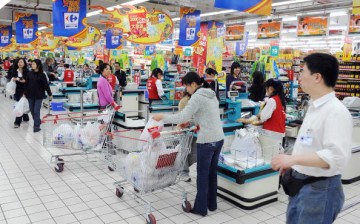 Chinese shoppers stand at the check-out counters inside a Carrefour supermarket store in the Gubei district of Shanghai.