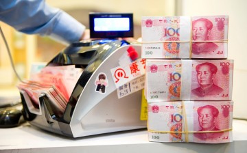 An employee counts Chinese Yuan bank notes in a Standard Chartered bank branch in Shanghai, China. 