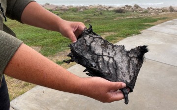 A spectator holds a piece of debris which was blown 5 miles (8 km) from the site where SpaceX test rocket SN11 exploded upon landing,