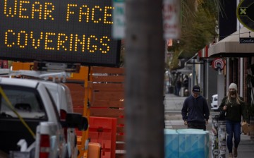 People walk past a sign warning to wear masks after California lifted its regional stay-at-home orders during the outbreak of the coronavirus disease (COVID-19), in Encinitas,