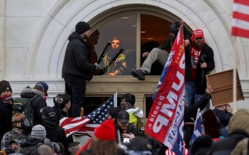 A mob of supporters of then-U.S. President Donald Trump climb through a window they broke as they storm the U.S. Capitol Building in Washington, U.S.,