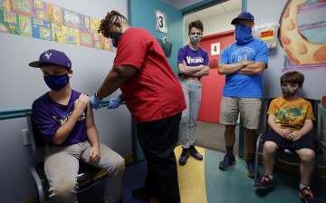 Family members look on as Jack Frilingos, 12, is inoculated with Pfizer's vaccine against coronavirus disease (COVID-19)