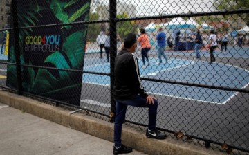 A man looks through a fence at a coronavirus disease (COVID-19) vaccination event for local adolescents and adults outside the Bronx Writing Academy school 