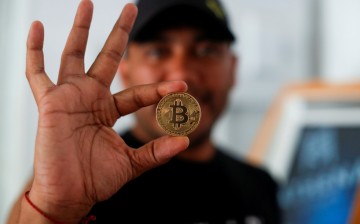 Bitcoin enthusiast Carlos Bonilla shows a physical representation of the cryptocurrency, at a Bitcoin Beach support office at El Zonte Beach in Chiltiupan,