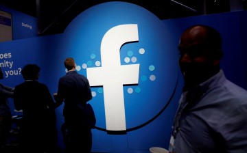 Attendees walk past a Facebook logo during Facebook Inc's F8 developers conference in San Jose, California, U.S