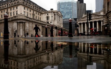 The Bank of England and Royal Exchange are reflected in a puddle as a pedestrian walks past, amid the coronavirus disease (COVID-19) outbreak in London, Britain