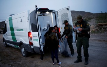 Migrants from Central America who were detained hand over their belongings to U.S. Border Patrol agents after crossing into the United States from Mexico