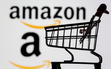 Small toy shopping cart is seen in front of displayed Amazon logo in this illustration,