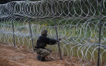 A Polish soldier builds a fence on the border between Poland and Belarus near the village of Nomiki, Poland