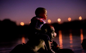 A migrant seeking refuge in the U.S. crosses the Rio Grande river with his son on shoulders, at the border towards Del Rio, Texas, U.S., as seen from Ciudad Acuna, Mexico