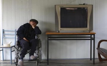 A man sleeps in a wheelchair next to a television set at a nursing home.
