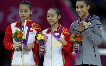 China's Deng Linlin (C) celebrates winning a gold medal in the women's gymnastics balance beam.