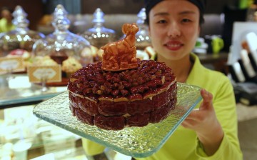 A waitress poses with a cake decorated with a goat-shaped chocolate, which is painted with edible gold powder, to celebrate the upcoming Chinese Lunar New Year.