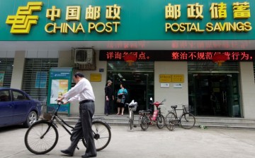 A man pushes his bicycle past a branch of China’s Postal Savings Bank. The lender’s recent announcement is seen by analysts as a bid to improve its corporate governance.